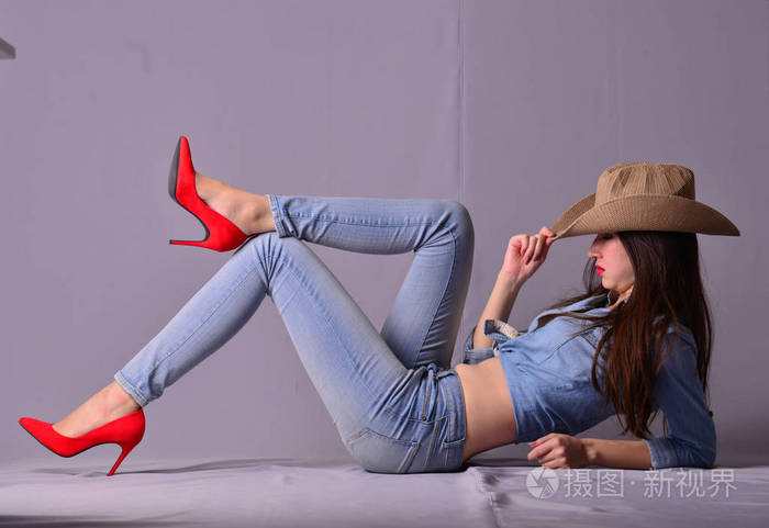 年轻的亚洲女人，长长的头发和灰色背景的腿牛仔风格模特