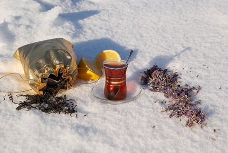 土耳其茶杯在雪与草本花和黄色柠檬