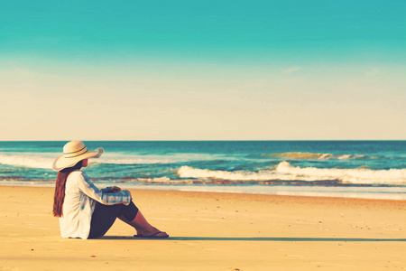 坐在沙滩上的一顶帽子的女人