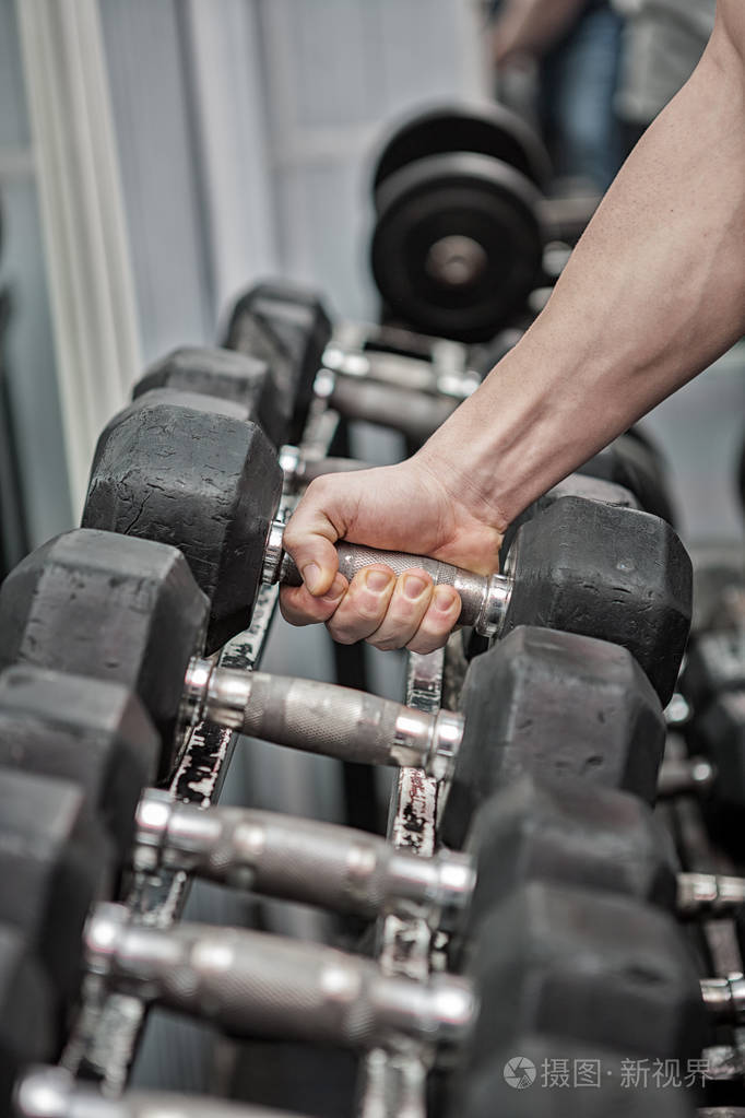 男人在健身房里挑选一个哑铃