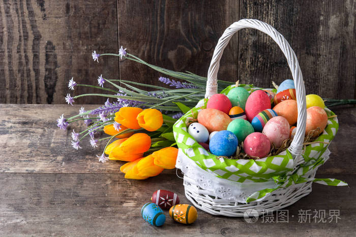 复活节彩蛋一篮子和木制背景上的花朵