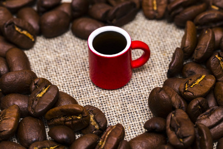 咖啡豆和一杯粗麻布背景上的心