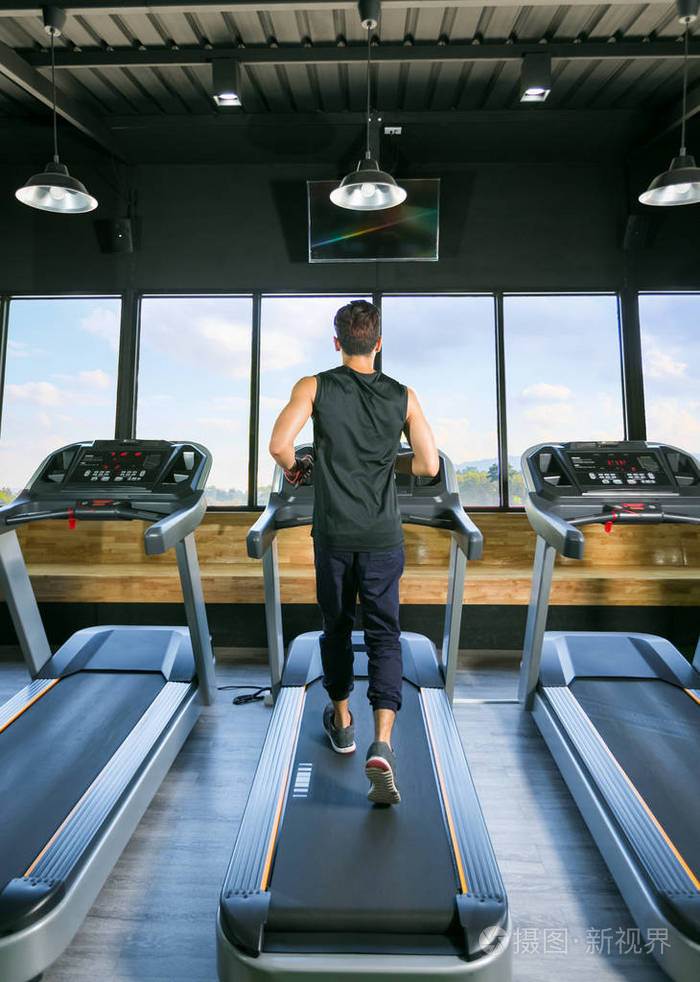 后视图的年轻男子运动员在健身房的跑步机上