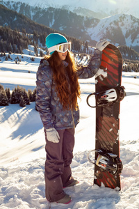 女孩的滑雪者站在山顶上与滑雪板在手中