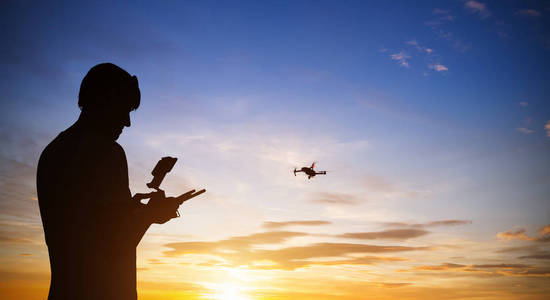无人驾驶飞机与直升机飞行员。落日的天空剪影
