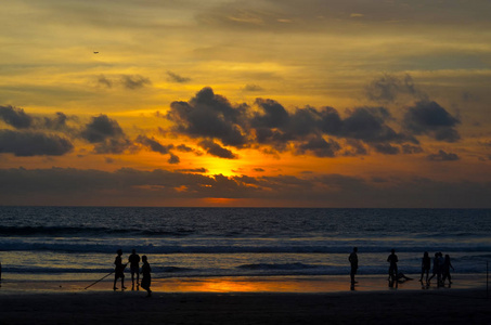 夕阳下的沙滩，黎明的夜空，云彩，橙色的海洋，人们的轮廓。