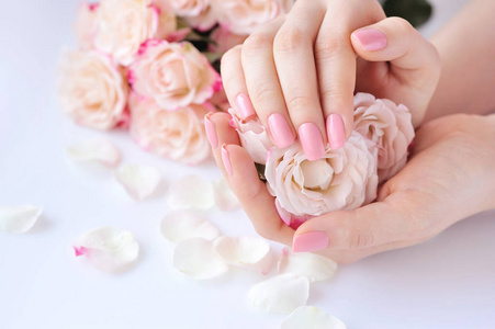 一个女人与粉红色指甲指甲和玫瑰的手