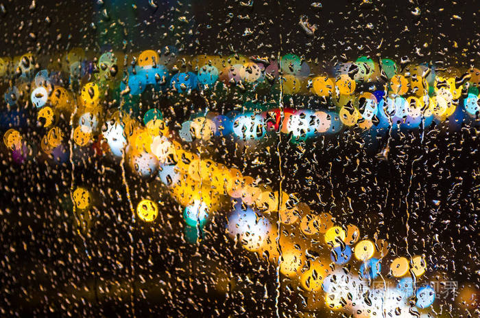 雨滴在玻璃和夜间城市的灯光