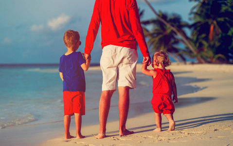 父亲和两个孩子在沙滩上行走