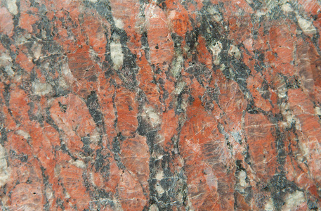 未抛光垫苍白粒状红色的花岗岩，细静脉结构与添加的黑色和白色的背景