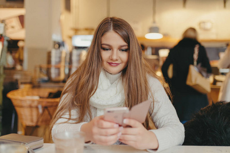 美丽的女孩，在智能手机在咖啡馆喝咖啡和发短信