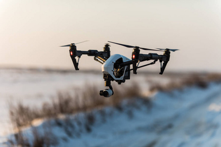 白无人机飞行和着陆在雪地上的数字相机
