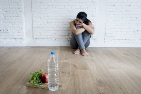 女人或十几岁的女孩坐在地面独自一人在家里担心遭受营养饮食失调症