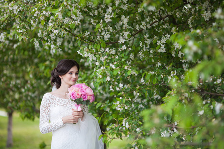 年轻漂亮的女人，在盛开的花园里的婚礼花束的新娘