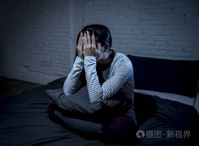 西班牙裔女人在家里卧室躺在床上,晚上很晚才入睡痛苦失眠