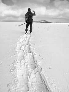 雪与背包拍照通过智能手机的人。徒步旅行者在雪堆里