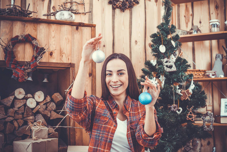 很漂亮，性格开朗的年轻女孩格子休闲衬衫圣诞树圣诞玩具在她手中的背景上布鲁内特的肖像。新的一年的概念。微笑和休息
