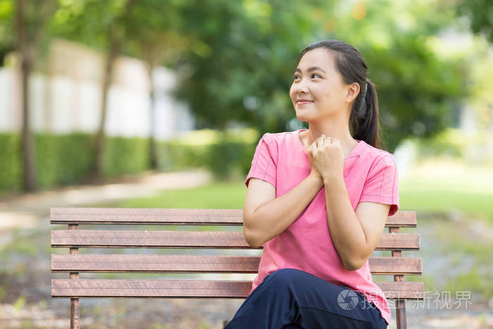 幸福的女人坐在公园的板凳上
