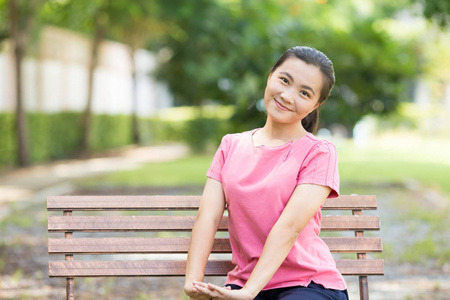 幸福的女人坐在公园的板凳上