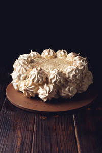 漂亮的白蛋白酥皮蛋糕站在木桌深色背景