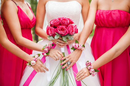 新娘手里拿着粉色的玫瑰花束。伴娘
