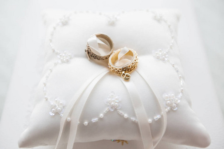 在白色的枕头上，用花边和珠结婚戒指