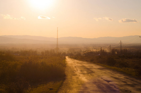 秋季或冬季景观与道路和树木。金光束日落。上的山脉和天空与云彩背景。阿塞拜疆高加索