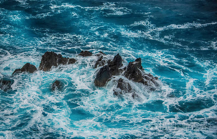 蓝色的汹涌海浪拍打在岩石上