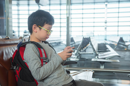 在机场的智能手机玩游戏的男孩图片