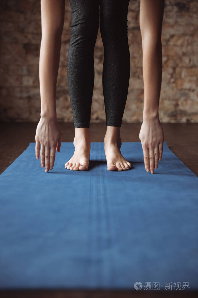 健身女人站赤脚和伸展在垫子上