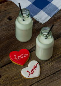 情人节曲奇饼和木制背景上一瓶牛奶