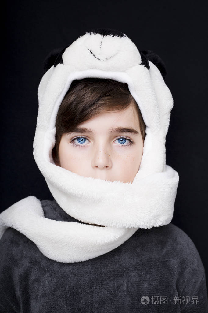 一个帅气的男孩，在黑色背景上的熊猫帽子的肖像