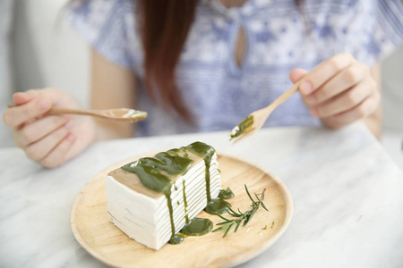 年轻亚洲女人吃绿茶绉蛋糕甜的食物
