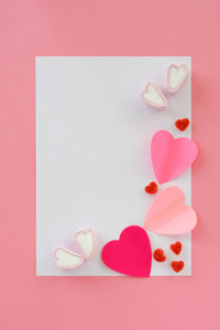 纸上的粉红色纸背景用纸做的爱心和红色的贴纸和糖果题词的地方的白床单。关于爱情的话题的背景文件。明亮的背景为题字的