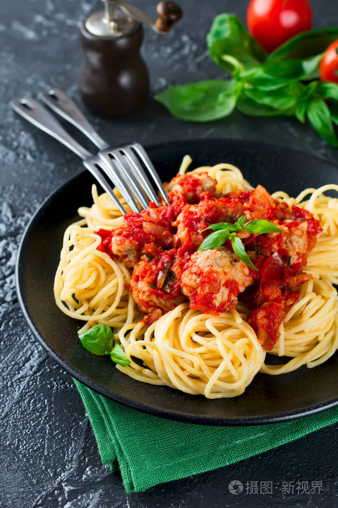 意大利面条意面配肉丸番茄酱和罗勒在深色背景上