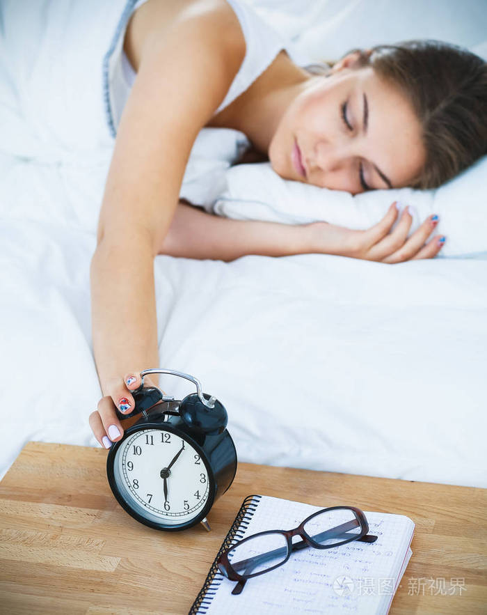 美丽的年轻女子躺在床上舒舒服服地和幸福照片-正版