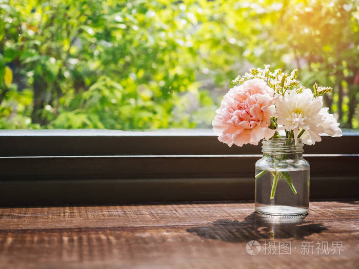 木制的桌子上的花康乃馨装饰玻璃