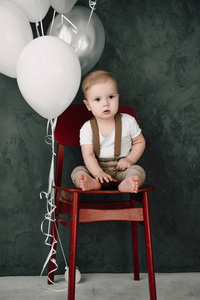 画像的可爱小男孩微笑庆祝 1 年生日快乐。一岁欧洲小绅士坐在椅子上，玩气球