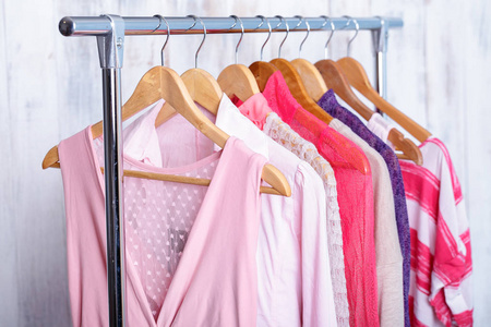 粉红色女性衣服挂在架子上在时尚存储。壁橱
