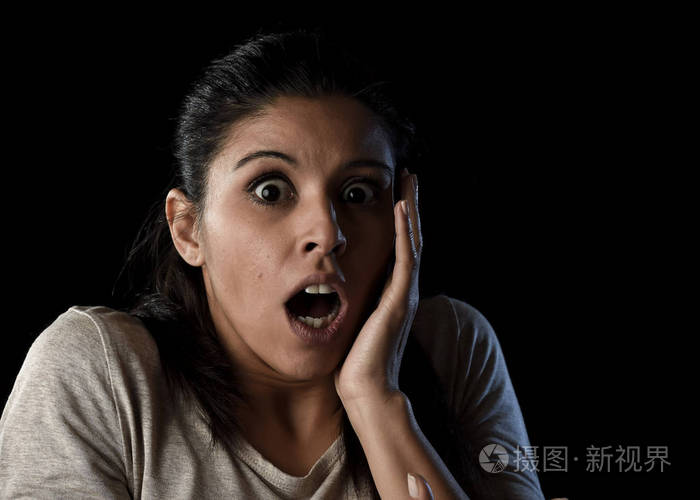 年轻美丽的害怕西班牙女人震动和惊讶的表情上黑色孤立