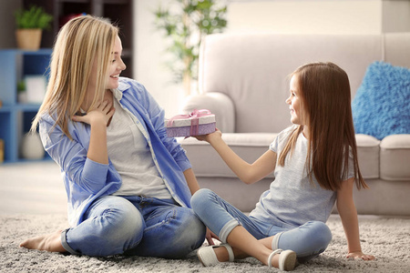 送礼给她母亲在家里的小女孩.母亲节的概念照片