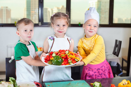 三个可爱的孩子们正在准备一份在厨房里的沙拉