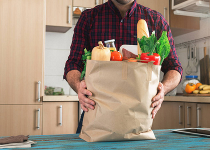 男人抱着不同的健康食物充分纸袋