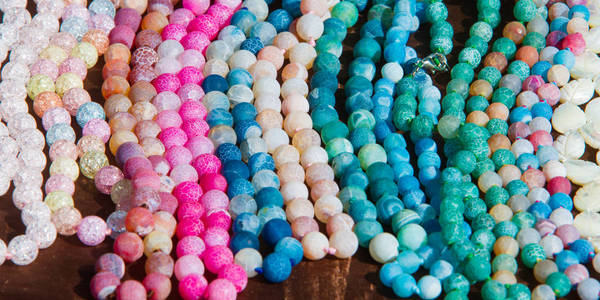 女性珠子。 一小块玻璃石或类似的材料，通常是圆形和穿孔的，用于与其他人一起作为项链或念珠或缝纫到织物上。