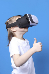 女孩穿着虚拟现实的护目镜和大拇指。蓝色背景上孤立