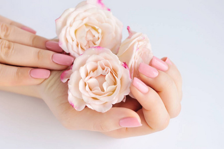 一个女人与粉红色指甲指甲和玫瑰的手