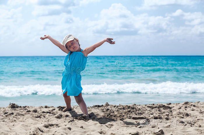 快乐的小女孩举起双手在沙滩上放松