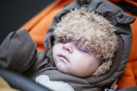 可爱的冬衣男婴睡在婴儿车里