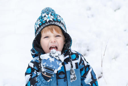 可爱的蹒跚学步的小男孩在冬天玩雪