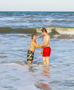 两个十几岁的男孩和兄弟在波涛汹涌的大海中享受海浪